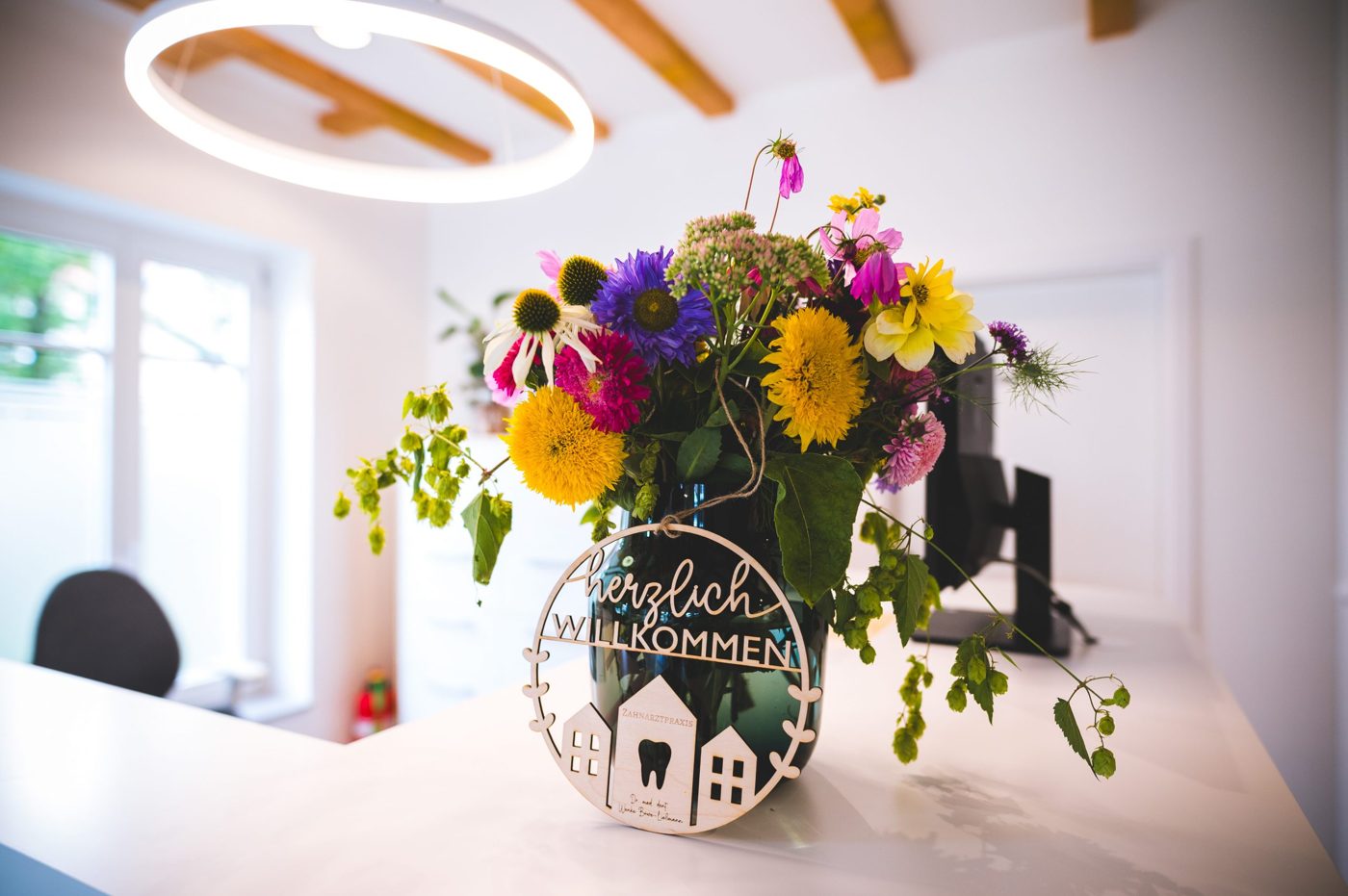 Blumenstrauß mit Schild „Herzlich Willkommen“ am Empfang